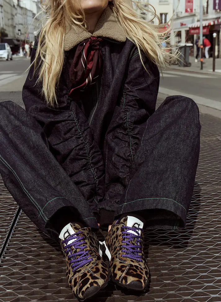 Person-wearing-a-dark-coat-and-leopard-print-shoes-on-a-city-street